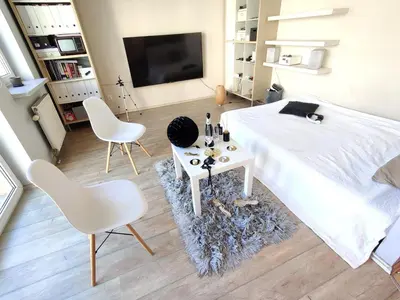 a bedroom with a bed and two chairs and a tv at Cozy Studio for a Couple - 10 min from the airport in Kraków