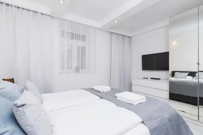 a white bedroom with a bed and a television at Comfy Apartment Lubelska Krakow by Noclegi Renters in Kraków