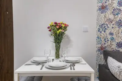 a table with plates and a vase of flowers on it at Cracow S31 in Kraków