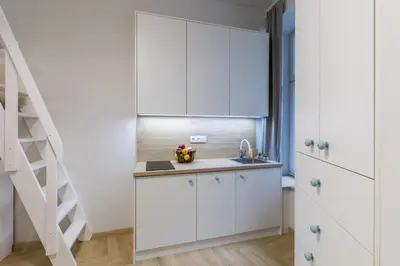 a kitchen with white cabinets and a staircase at Cracow S31 in Kraków