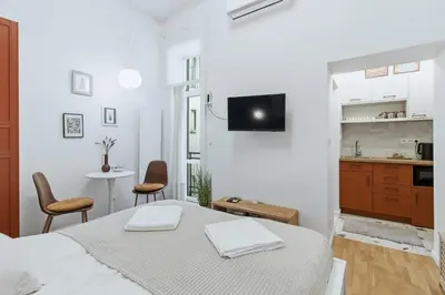 a white room with a bed and a kitchen at Apartament Targowy by LookAp in Kraków