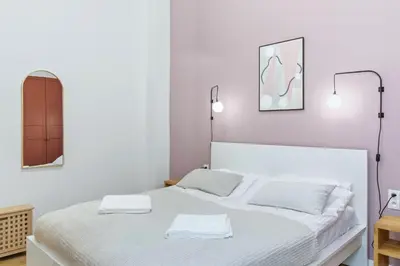 a white bedroom with two beds and a mirror at Apartament Targowy by LookAp in Kraków