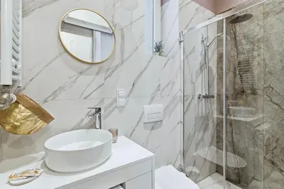 a white bathroom with a sink and a shower at Apartament Targowy by LookAp in Kraków