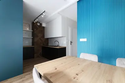 a kitchen and dining room with a wooden table and blue walls at Prandoty 10B by Homeprime in Kraków