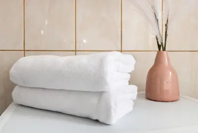 a stack of towels on a counter with a vase at Malila Premium Apartments Cracow Sebastiana 17 Old Town in Kraków