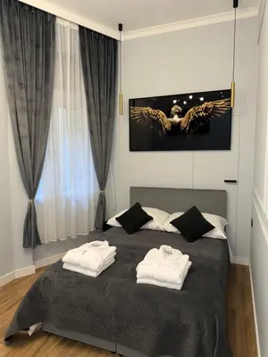 a bedroom with a bed with two towels on it at Apartament Grey Prywatne Jacuzzi Miodowa Kraków in Kraków