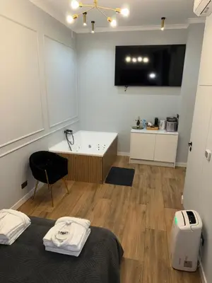 a room with a bed and a tv on a wall at Apartament Grey Prywatne Jacuzzi Miodowa Kraków in Kraków