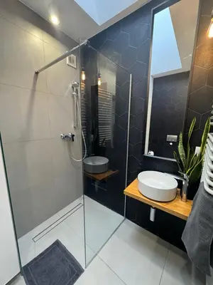 a bathroom with a glass shower stall and a sink at Grodzka Loft in Kraków