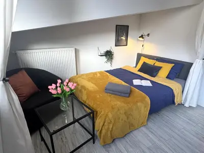 a bedroom with a bed and a table with a vase of flowers at Grodzka Loft in Kraków