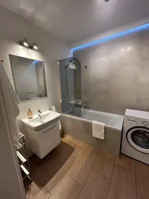 a bathroom with a tub and a sink and a washing machine at Solna Studio Apartment - Comfort Stay in Heart of Kraków in Kraków