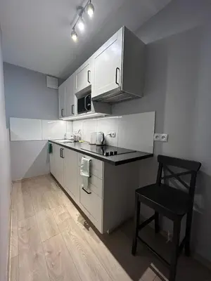 a kitchen with white cabinets and a chair in it at Solna Studio Apartment - Comfort Stay in Heart of Kraków in Kraków
