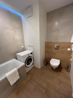 a bathroom with a washing machine and a white tub at Solna Studio Apartment - Comfort Stay in Heart of Kraków in Kraków