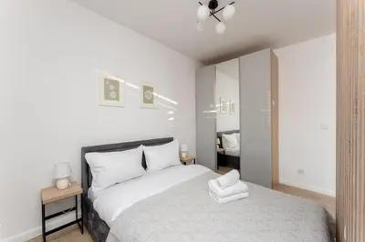 a white bedroom with a bed and a mirror at Ciesielskiego Cozy Studio by BookingHost in Kraków