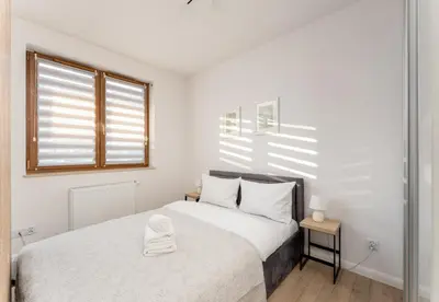 a white bedroom with a bed and a window at Ciesielskiego Cozy Studio by BookingHost in Kraków