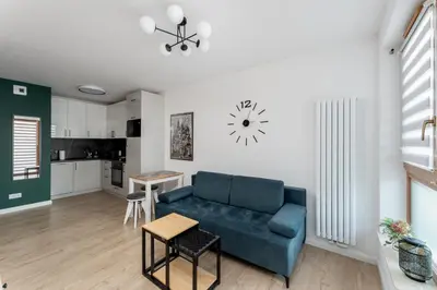 a living room with a blue couch and a kitchen at Ciesielskiego Cozy Studio by BookingHost in Kraków