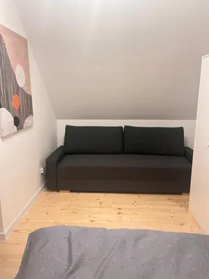 a living room with a black couch in a room at Słoneczny Zakątek 2025