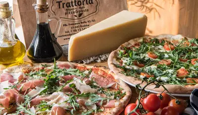 two pizzas on a table next to a block of cheese at Prywatny apartament przy ulicy Francesco Nullo in Kraków