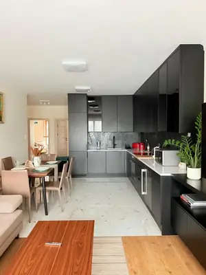 a kitchen with black cabinets and a dining room at Prywatny apartament przy ulicy Francesco Nullo in Kraków