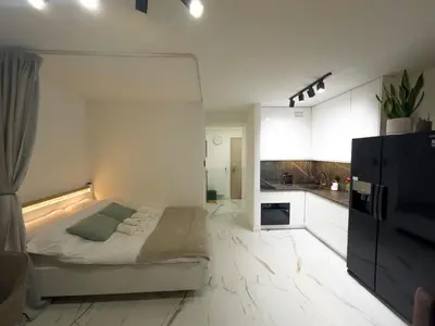 a white room with a bed and a kitchen at Apartament Dobrego Pasterza 46 Free Parking in Kraków