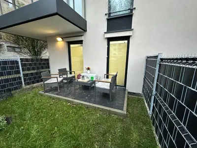 a patio with two chairs and a table in the grass at Apartament Dobrego Pasterza 46 Free Parking in Kraków