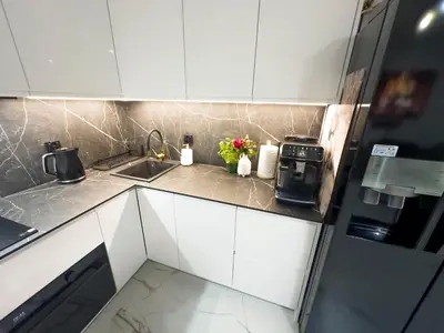 a kitchen with white cabinets and a sink and flowers at Apartament Dobrego Pasterza 46 Free Parking in Kraków