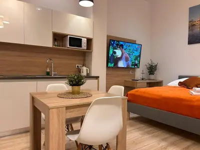 a bedroom with a bed and a table and a kitchen at Old Town Apartments B15 in Kraków