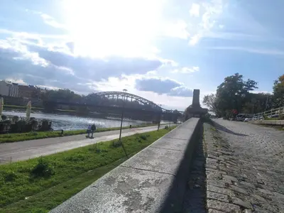a bridge over a river with a person walking on a sidewalk at Appartement au coeur de Kazimierz in Kraków