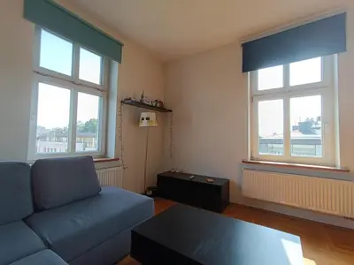 a living room with a couch and two windows at Appartement au coeur de Kazimierz in Kraków