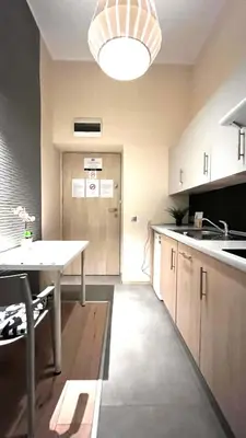 a kitchen with a table and a hallway with a door at Small Studio for 1 in Kraków