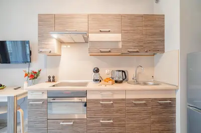 a kitchen with wooden cabinets and a sink at Kraków Grzegórzki Apartment with Balcony - by Rentujemy in Kraków