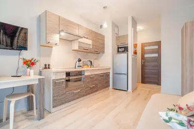 a kitchen with wooden cabinets and a desk in a room at Kraków Grzegórzki Apartment with Balcony - by Rentujemy in Kraków