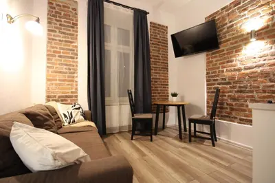a living room with a couch and a brick wall at Krakow Central Vintage Apartment by Rently in Kraków