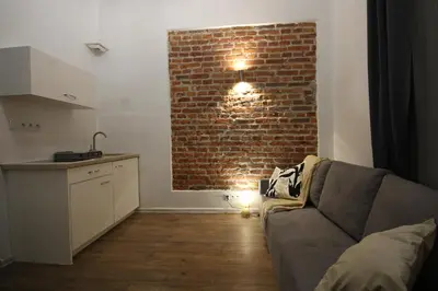 a living room with a couch and a brick wall at Krakow Central Vintage Apartment by Rently in Kraków