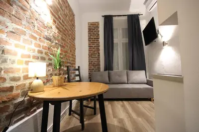 a living room with a table and a brick wall at Krakow Central Vintage Apartment by Rently in Kraków
