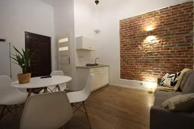 a living room with a table and a brick wall at Krakow Central Vintage Apartment by Rently in Kraków