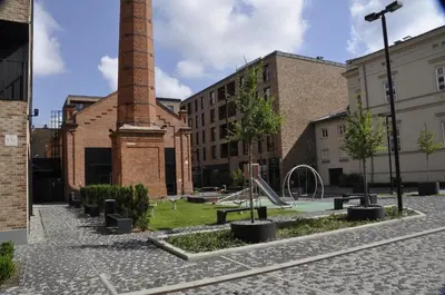 an empty courtyard with a brick chimney and a playground at Holiday Apartments Browar Lubicz Krakow Stare Miasto in Kraków