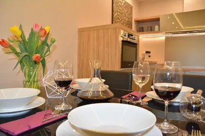 a table with glasses of wine and flowers on it at Holiday Apartments Browar Lubicz Krakow Stare Miasto in Kraków
