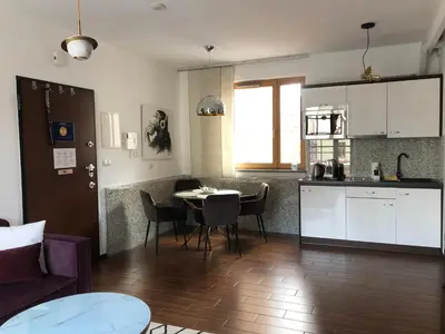 a kitchen and a living room with a table and chairs at Holiday Apartments Browar Lubicz Krakow Stare Miasto in Kraków