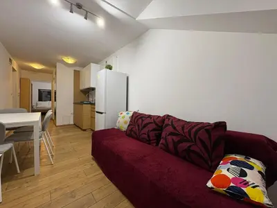 a living room with a red couch and a white refrigerator at Kraków Riverside & Old Town Apartment in Kraków