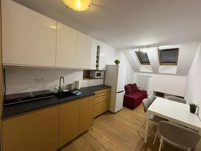 a kitchen with a refrigerator and a table with a red couch at Kraków Riverside & Old Town Apartment in Kraków