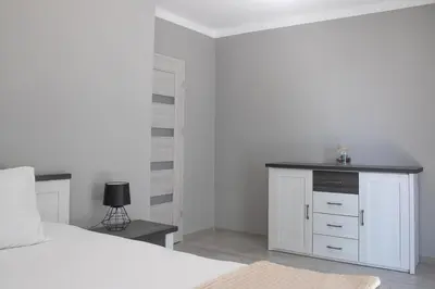 a white vase with purple flowers in it on a table at Cracow Modern Apartment FREE Parking, Views, Tram in Kraków