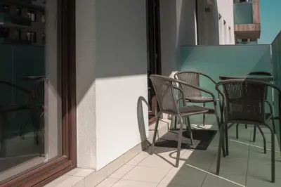 a group of chairs and a table on a balcony at Cracow Modern Apartment FREE Parking, Views, Tram in Kraków