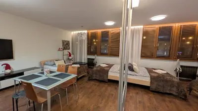 a room with two beds and a table and a dining room at KrakowApart Dietla in Kraków