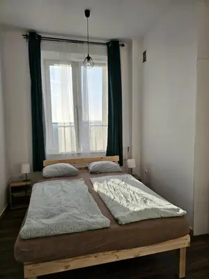 two beds in a bedroom with a large window at W1 PRIVATE rooms in Kraków