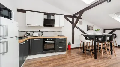 a kitchen with black cabinets and a table with chairs at Sunshine Loft Cracow, Sun & Snow in Kraków