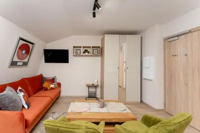 a living room with an orange couch and green chairs at Kraków Główny Comfort Studio by BookingHost in Kraków