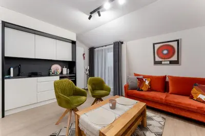 a living room with a orange couch and green chairs at Kraków Główny Comfort Studio by BookingHost in Kraków