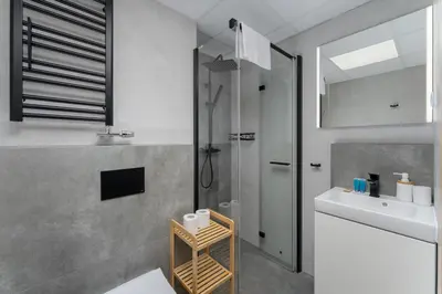 a bathroom with a shower and a sink and a mirror at Kraków Główny Comfort Studio by BookingHost in Kraków