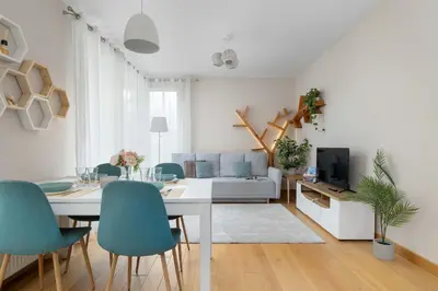 a living room with a white table and blue chairs at Family Apartment in Cracow with Parking, Desk and Bathtub by Noclegi Renters in Kraków