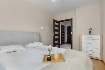 a bed with a tray with two candles and flowers on it at Family Apartment in Cracow with Parking, Desk and Bathtub by Noclegi Renters in Kraków